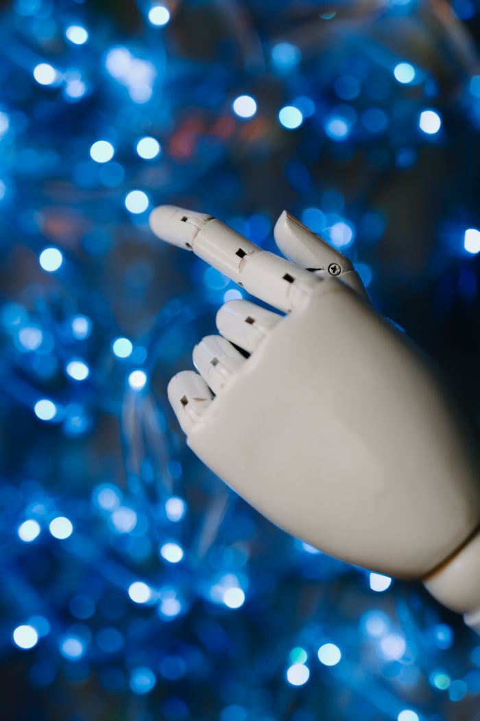 ours-journey Close-up of a robotic hand with glowing blue bokeh background, symbolizing advanced technology.